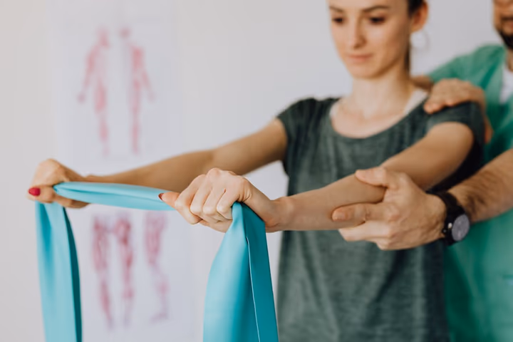 Orthopédiste en uniforme appliquant un bandage élastique sur le bras d'une jeune femme dans un cabinet médical