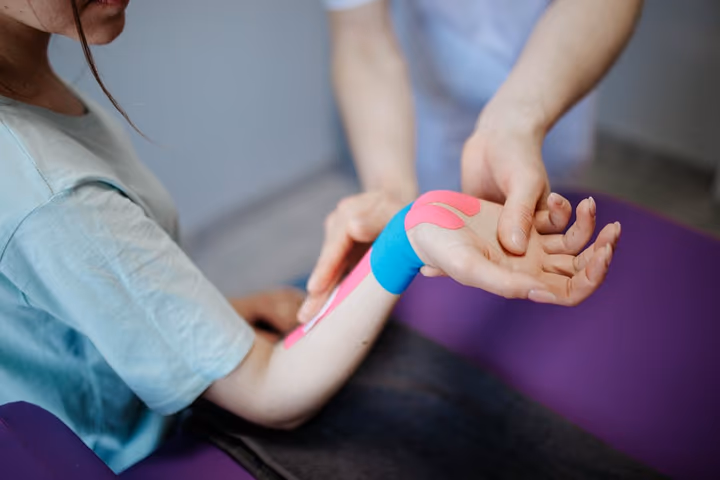 Thérapeute appliquant du ruban kinésiologique sur la peau d'un patient pour soulager la douleur.